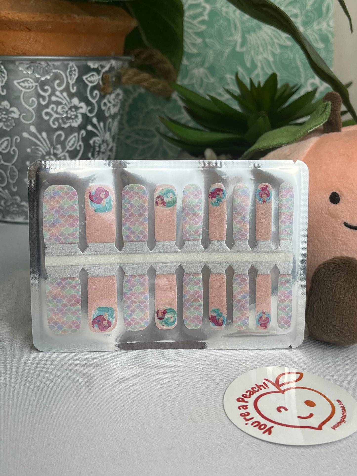 Pastel mermaid nail polish strips with scale and character designs in clear retail packaging