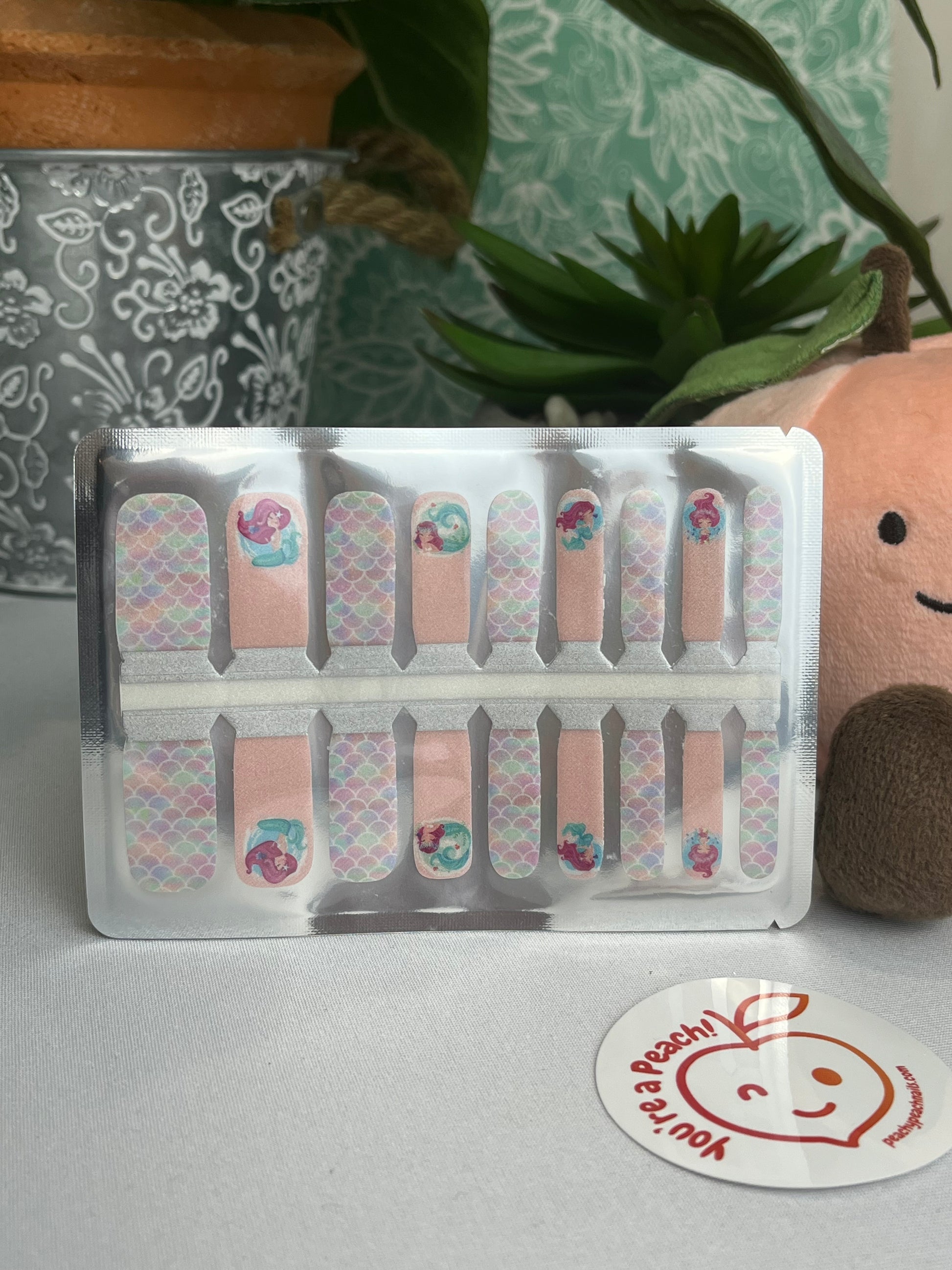 Pastel mermaid nail polish strips with scale and character designs in clear retail packaging