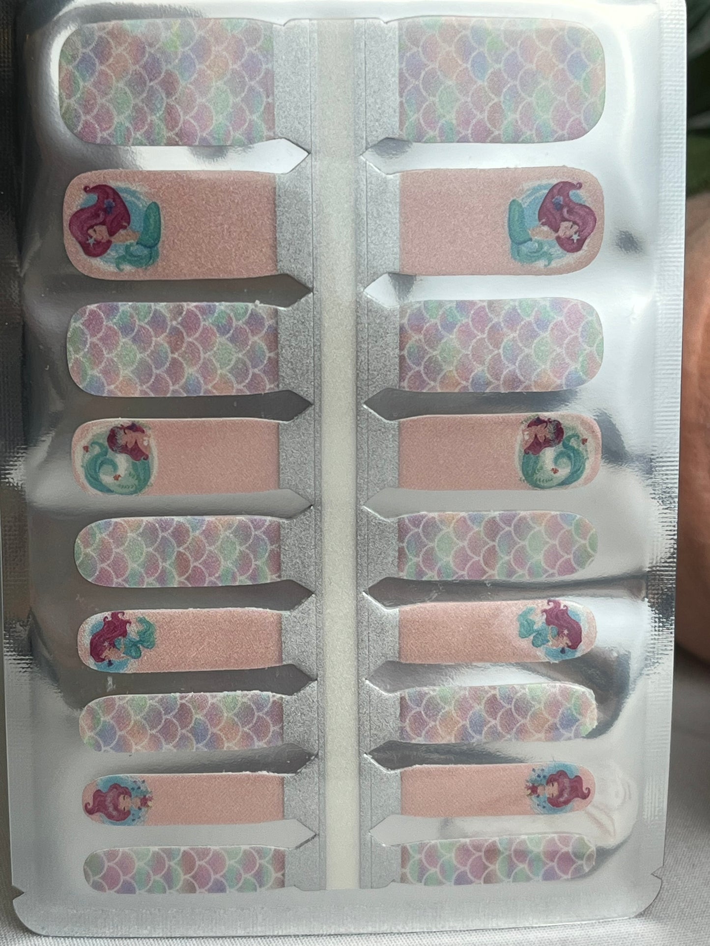 Mermaid nail strips in pastel colors, featuring colorful scale patterns and mermaid character designs.