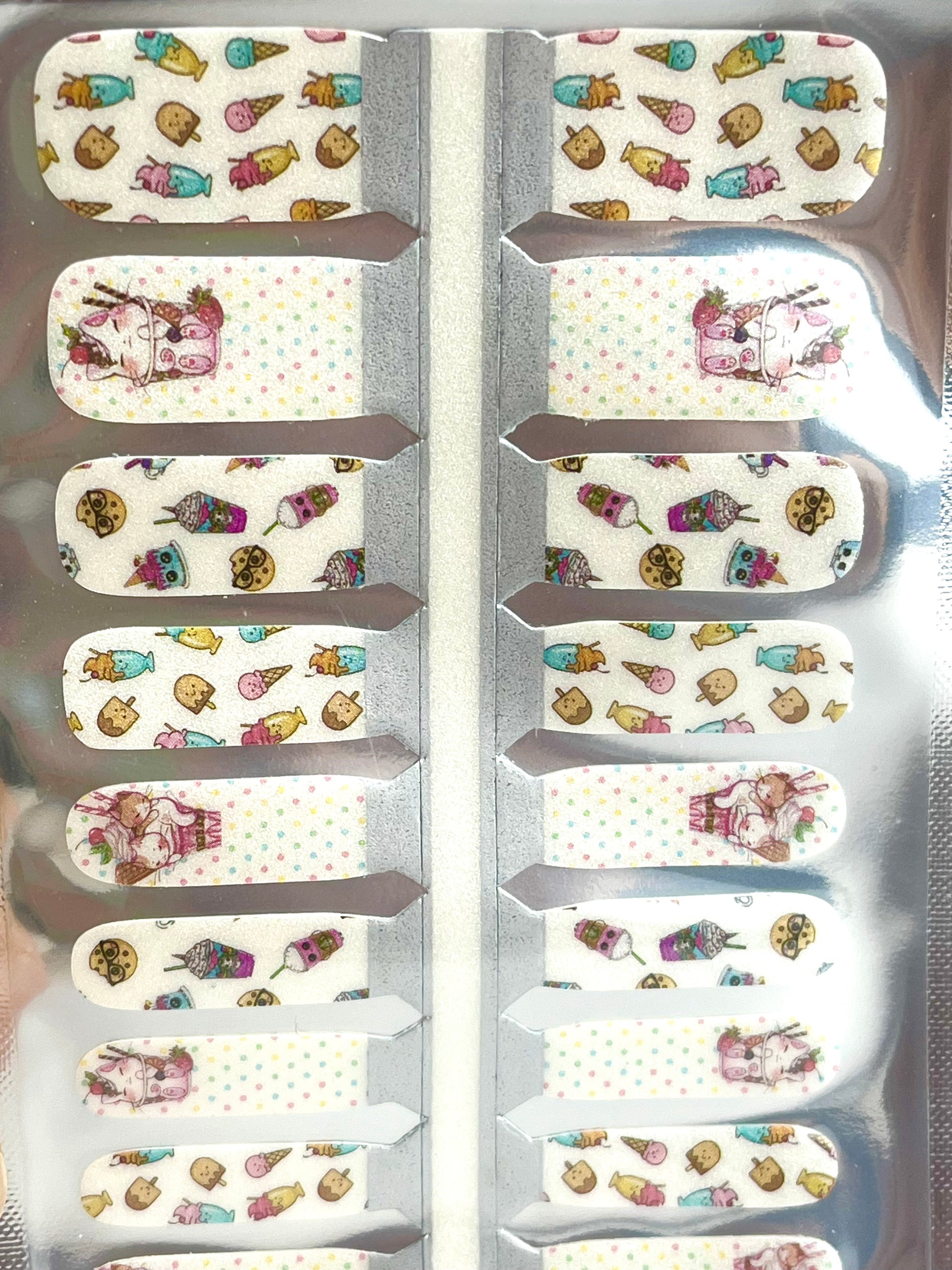 Sheet of kawaii dessert nail wraps with ice cream cones, milkshakes, cookies, and animal designs on a dotted white background.