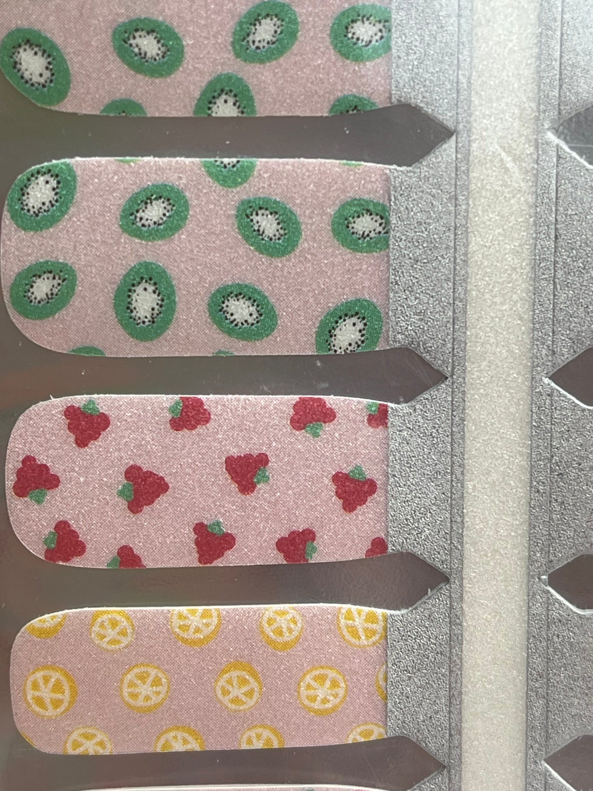 Pink nail strips with kiwi, strawberry, and lemon fruit patterns, ideal for DIY nail art.