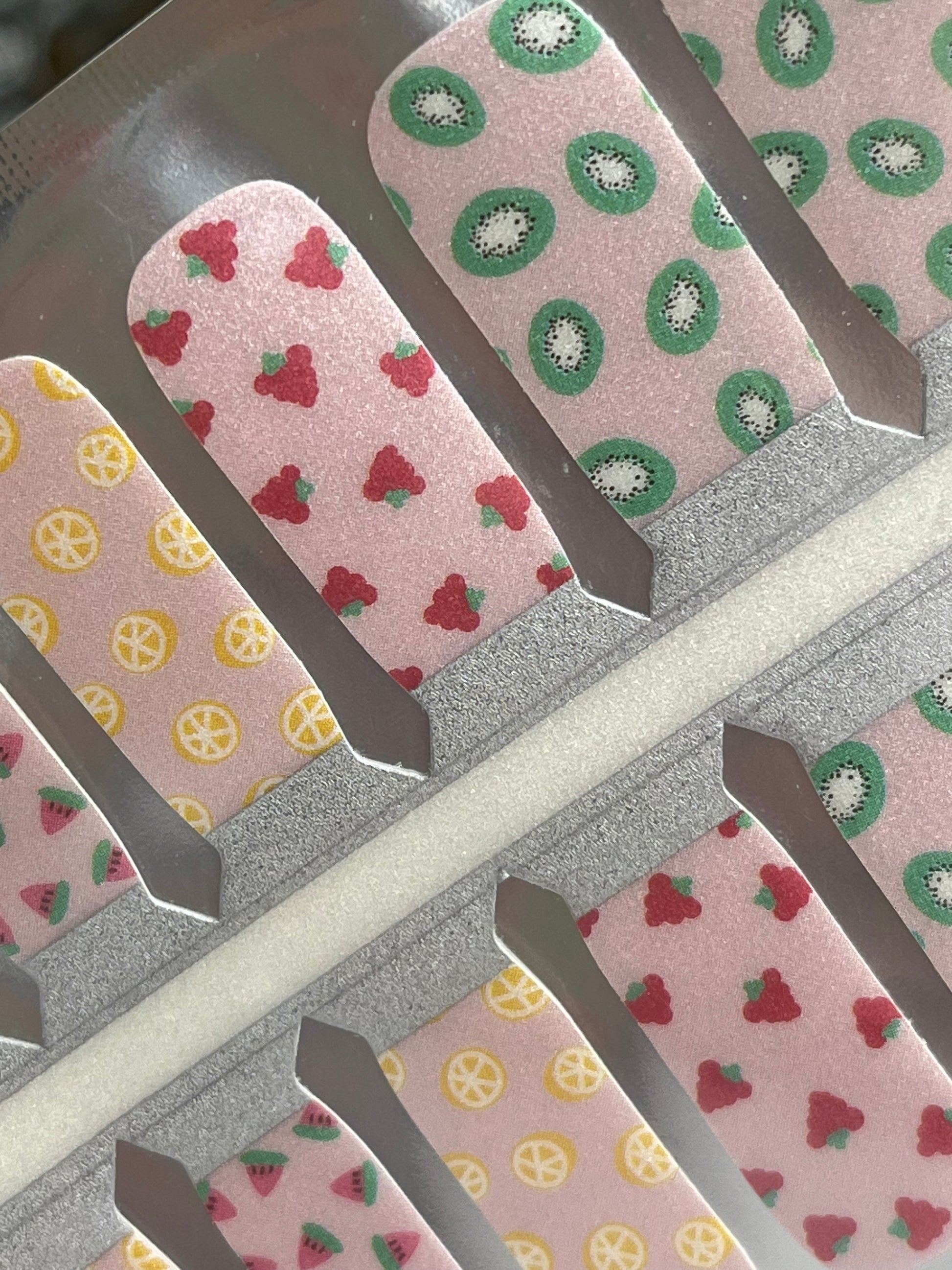 Pink fruit-patterned nail strips featuring kiwi, lemon, strawberry, and watermelon designs.