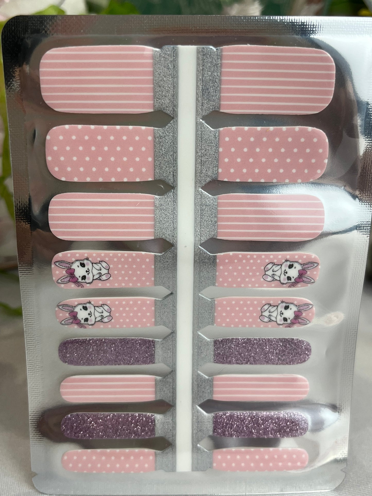 Sheet of pink and purple glitter nail wraps with stripes, polka dots, and cute bunny designs in clear packaging.