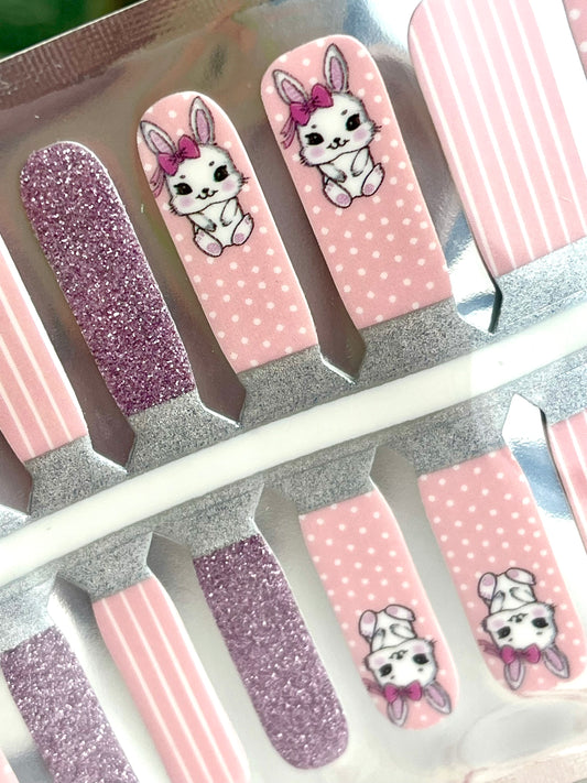Set of pink and purple glitter nail strips featuring cute white bunnies with pink bows, polka dots, and vertical stripes.