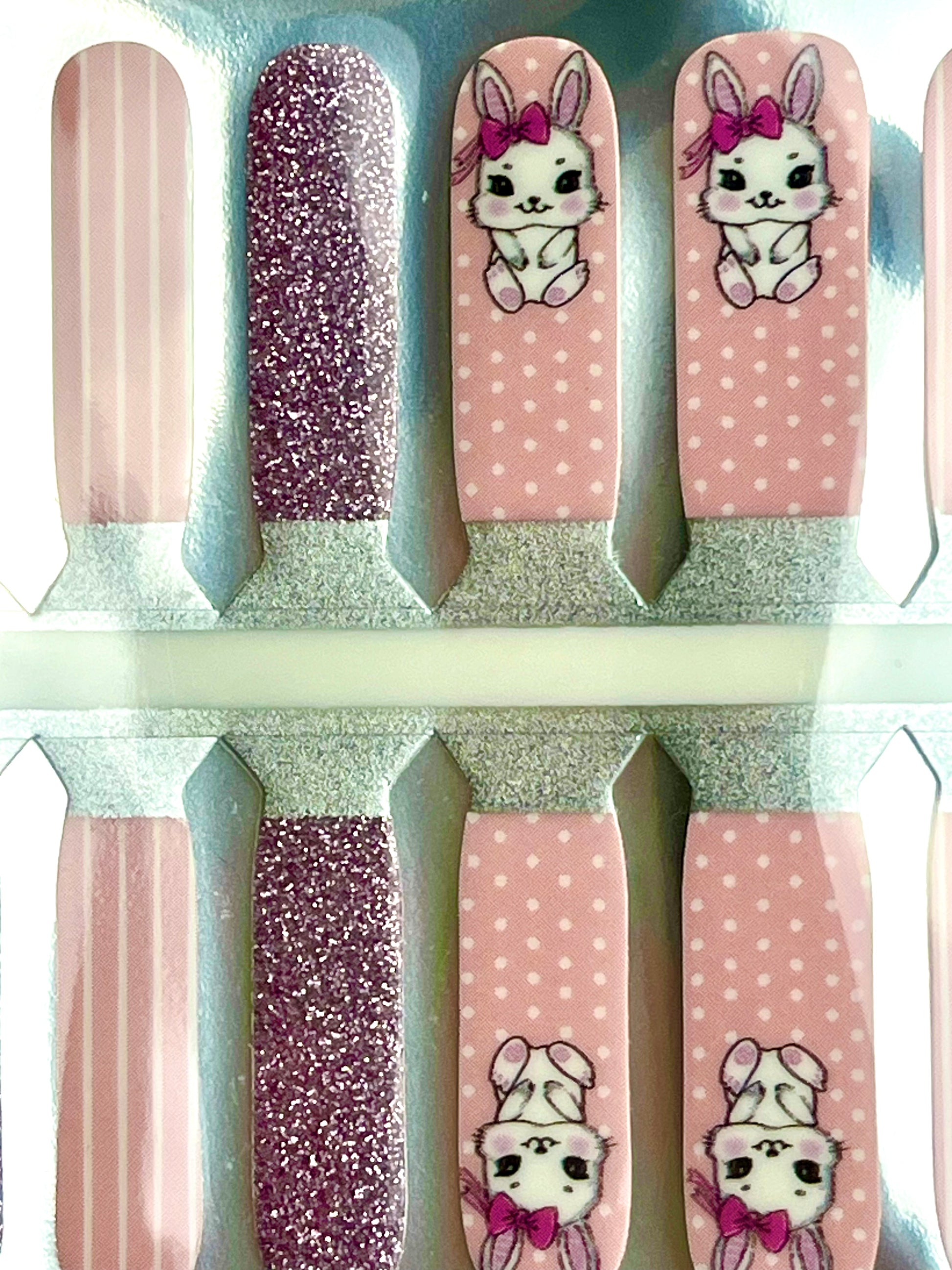 Pink glitter and patterned nail polish strips featuring cute bunnies, polka dots, and stripes.